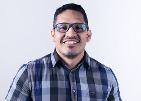 Casual portrait of a smiling man wearing glasses and a plaid shirt.